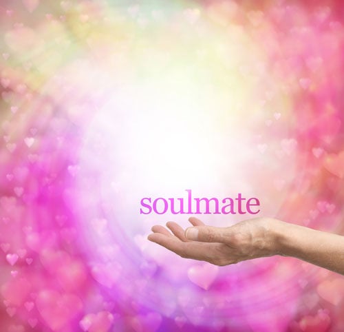 Cosmic pink and green stars in the shape of hearts with an outstretched hand holding the word "soulmate"